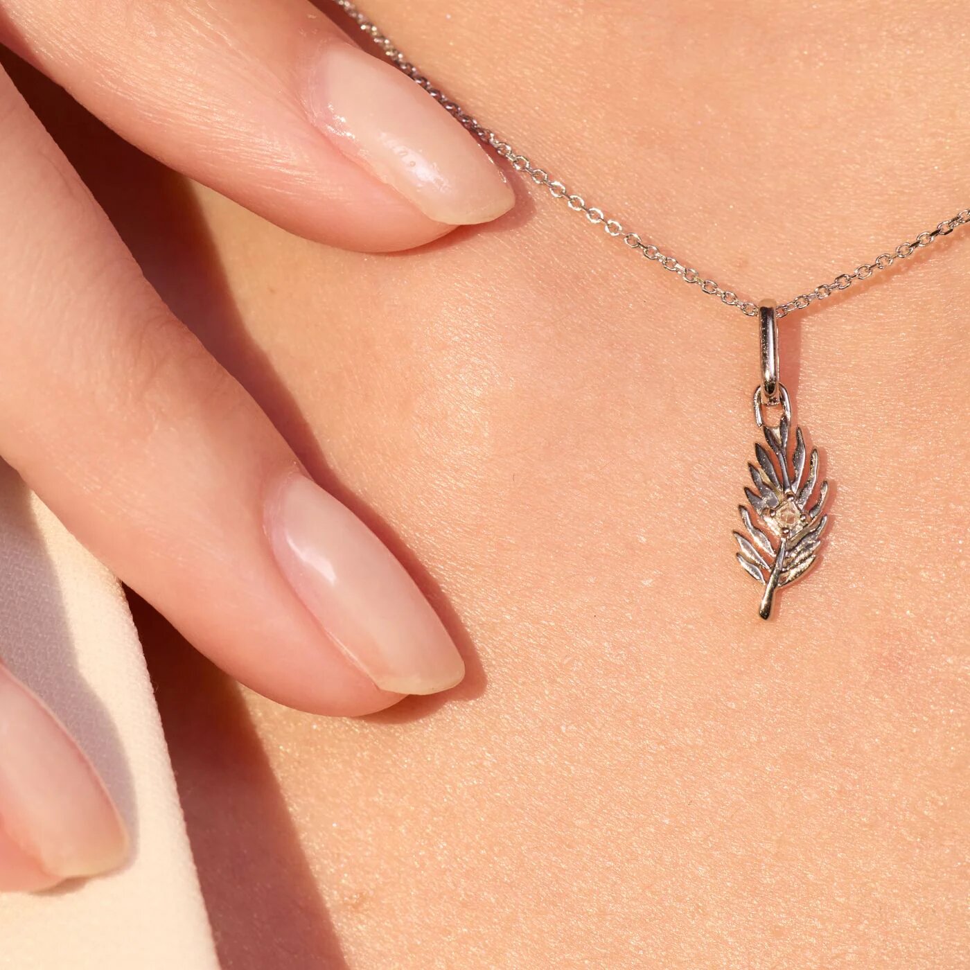 Close-up of a leaf pendant necklace with a small gemstone resting on skin, symbolizing inner strength, growth, and resilience