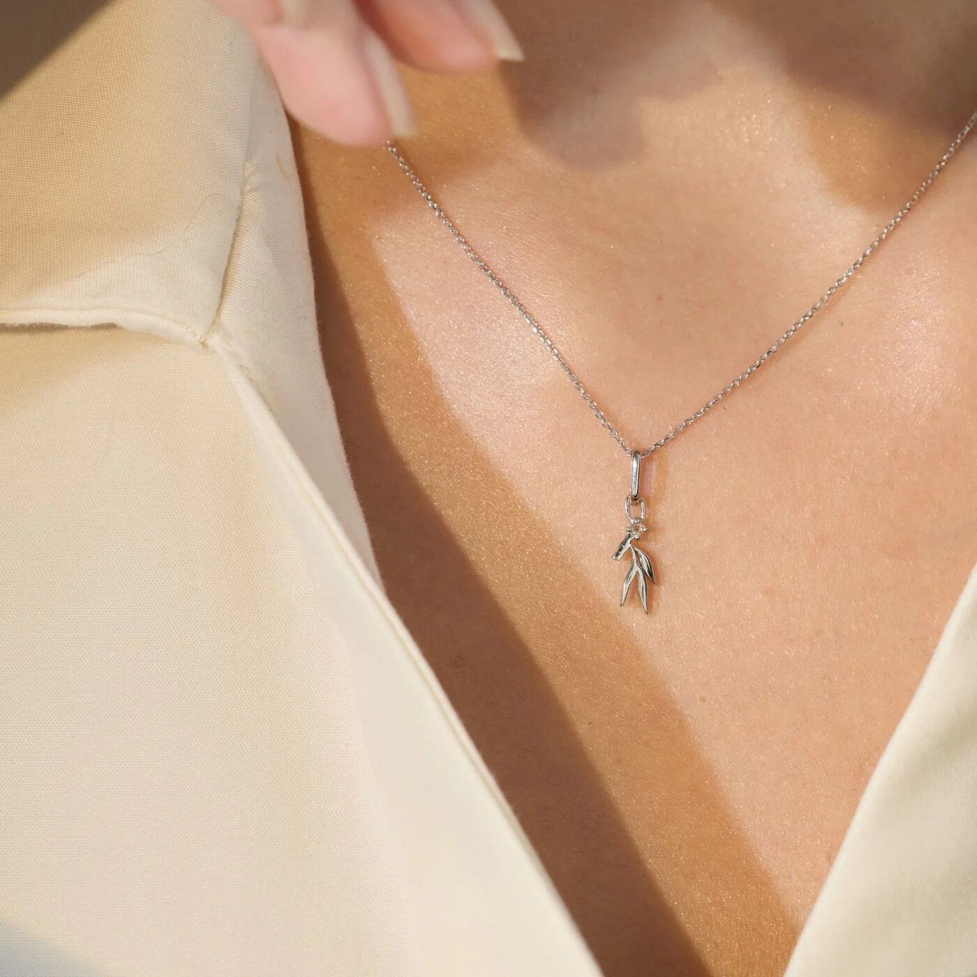 Close-up of a delicate necklace with a leaf pendant worn on chest, symbolizing spiritual growth, awakening, and inner clarity